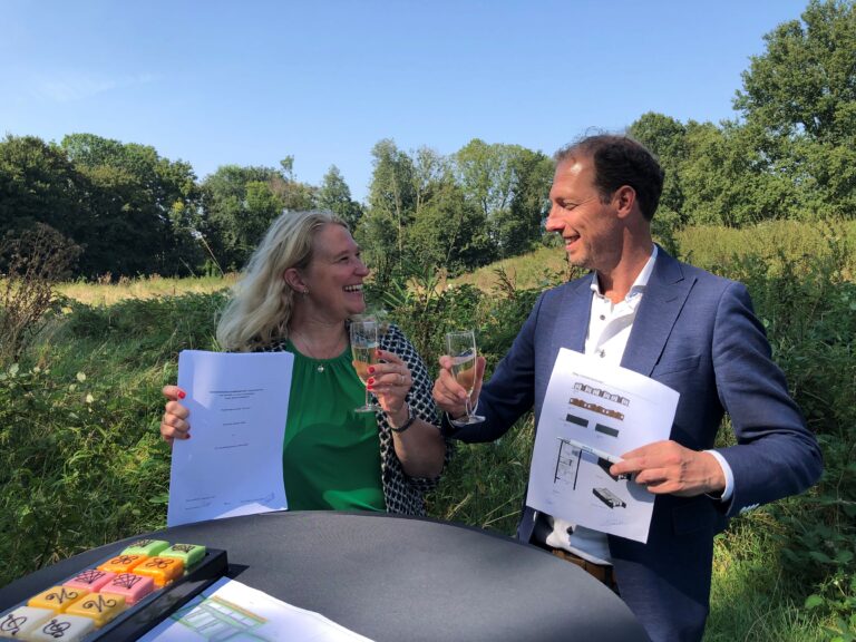 Karin van Vliet en Mark Drost ondertekenen op de projectlocatie bij sportpark De Heul een overeenkomst over de bouw van 40 flexwoningen in Loenen.